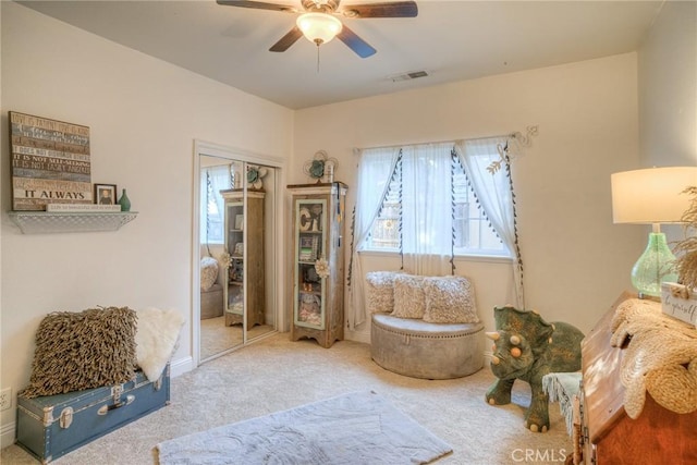 living area featuring carpet flooring and ceiling fan