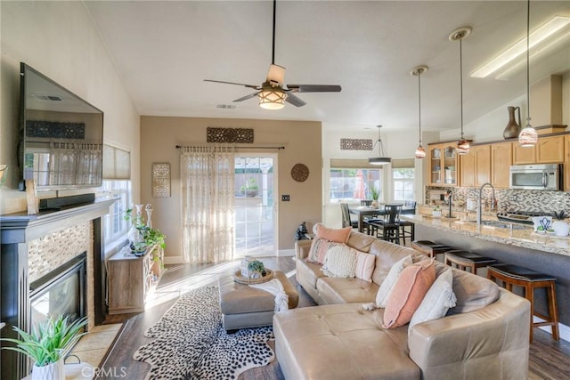 living room featuring a tile fireplace, plenty of natural light, lofted ceiling, and sink