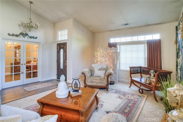 interior space featuring vaulted ceiling, french doors, plenty of natural light, and an inviting chandelier