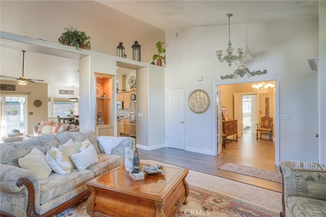 living room featuring hardwood / wood-style flooring, ceiling fan with notable chandelier, and high vaulted ceiling