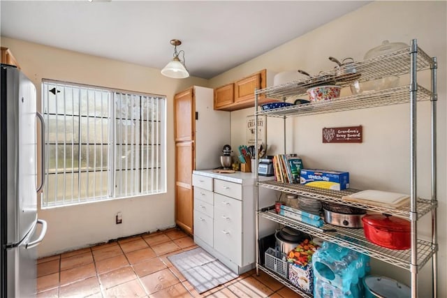 kitchen with light brown cabinets, light tile patterned floors, decorative light fixtures, and stainless steel refrigerator