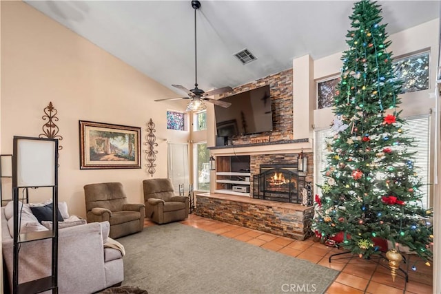 living room with light tile patterned floors, vaulted ceiling, a stone fireplace, and ceiling fan