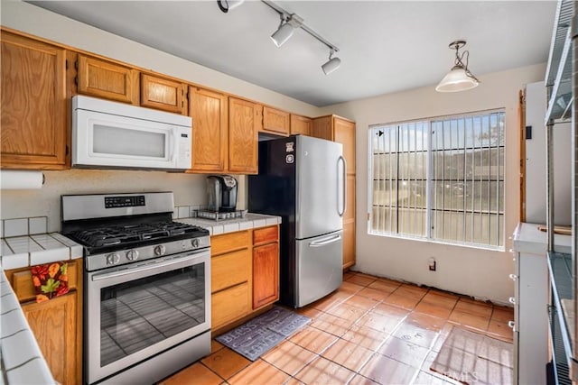 kitchen with tile countertops, pendant lighting, track lighting, light tile patterned floors, and stainless steel appliances