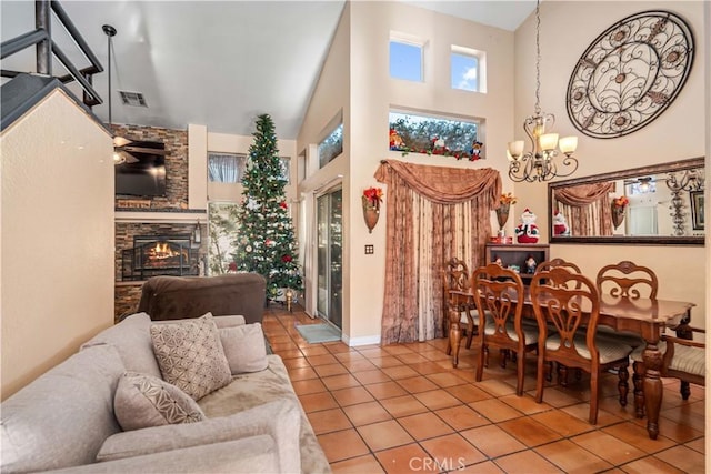 tiled dining area featuring a fireplace, a towering ceiling, and ceiling fan with notable chandelier