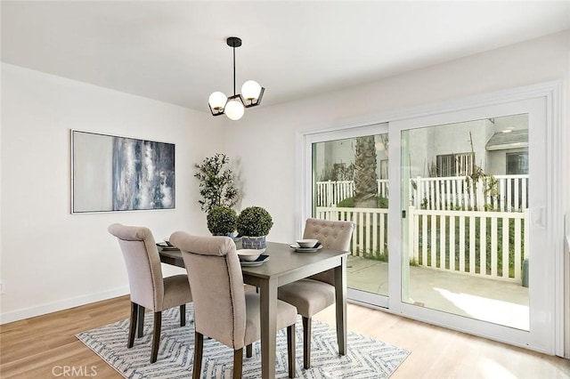 dining space with hardwood / wood-style floors, a healthy amount of sunlight, and an inviting chandelier