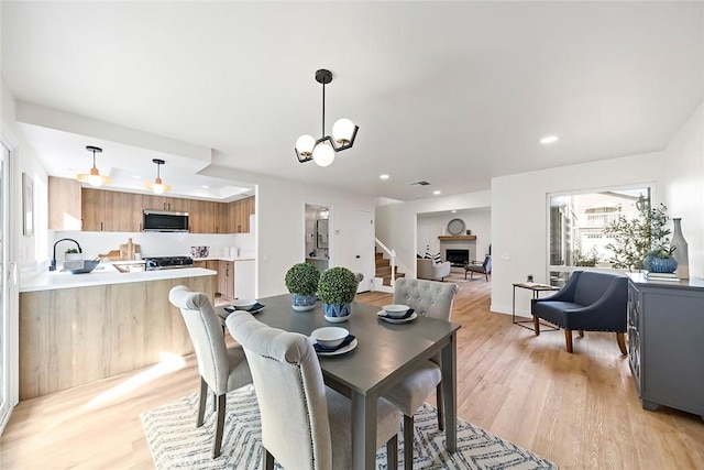 dining area featuring sink, light hardwood / wood-style flooring, and a notable chandelier