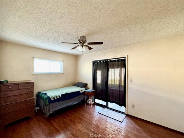 bedroom with ceiling fan, a textured ceiling, dark hardwood / wood-style flooring, and access to outside