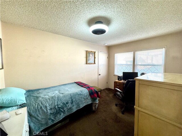 bedroom featuring a textured ceiling and dark carpet