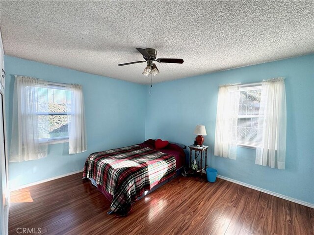 bedroom with ceiling fan, dark hardwood / wood-style flooring, and a textured ceiling