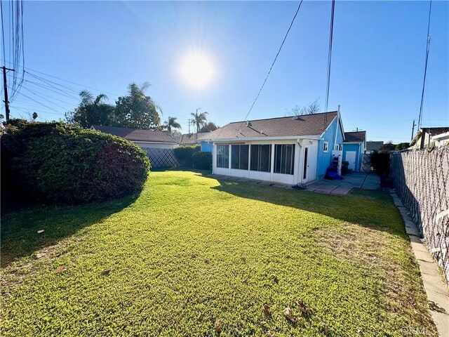 back of house featuring a yard and a sunroom