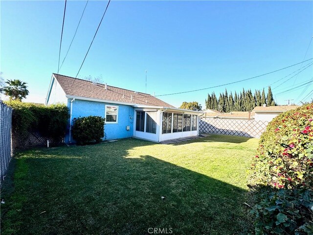 back of property featuring a sunroom and a lawn