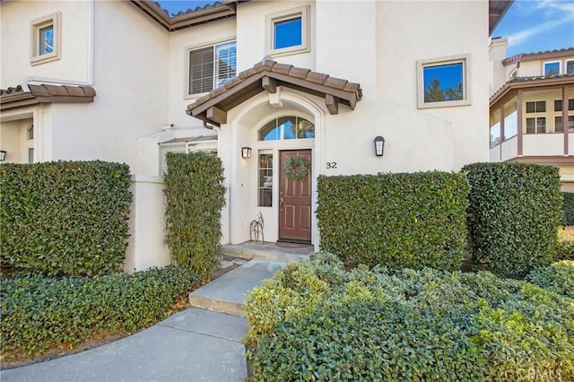 doorway to property featuring a tile roof and stucco siding