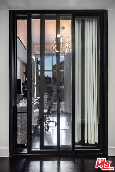 doorway with hardwood / wood-style flooring and a notable chandelier