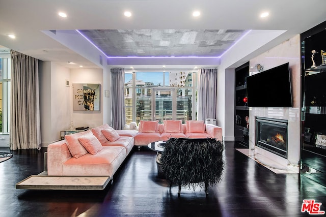 living room with dark hardwood / wood-style floors, a fireplace, and a raised ceiling