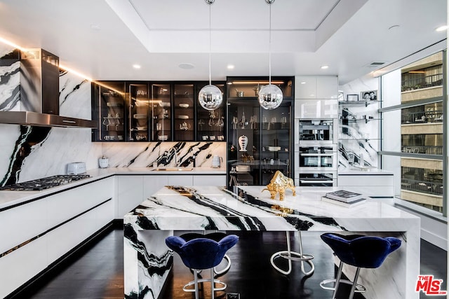 kitchen with white cabinetry, island range hood, decorative backsplash, and pendant lighting