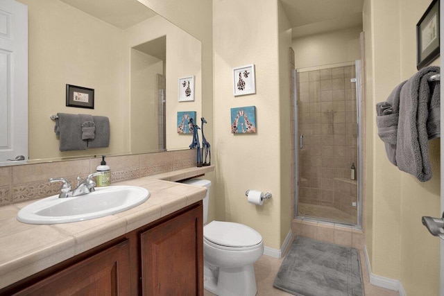 bathroom featuring vanity, backsplash, toilet, and a shower with door