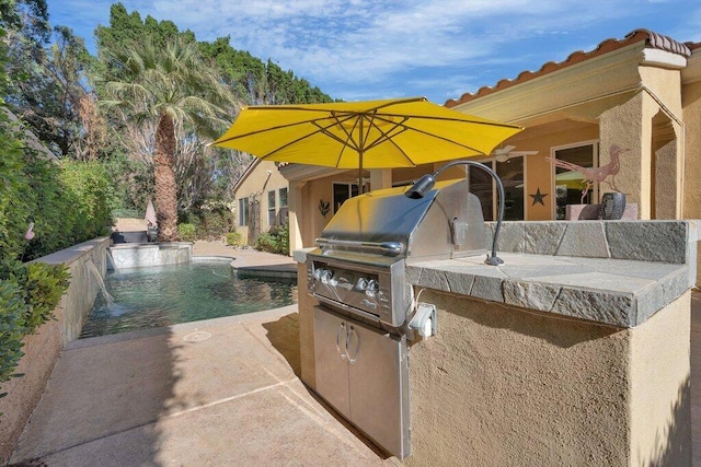 view of patio / terrace with a grill, pool water feature, and an outdoor kitchen