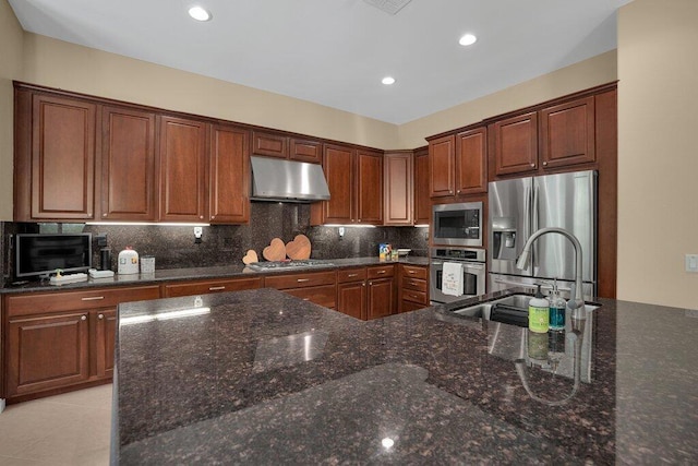 kitchen featuring sink, stainless steel appliances, dark stone counters, decorative backsplash, and light tile patterned floors