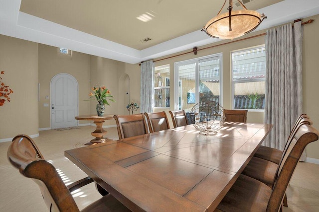 tiled dining area with a tray ceiling