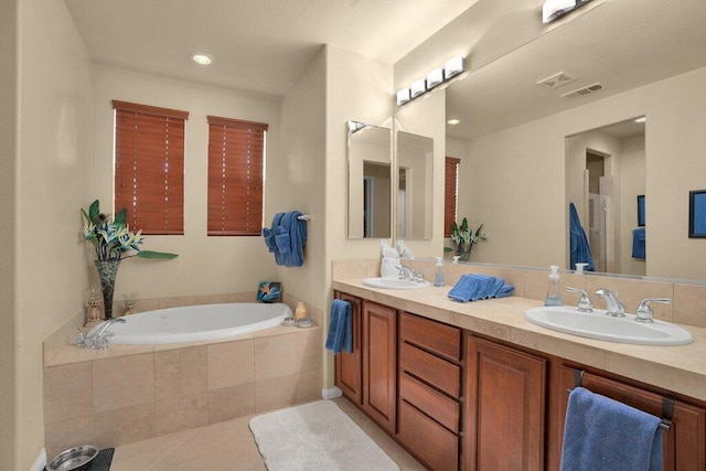 bathroom featuring tile patterned floors, tiled bath, and vanity