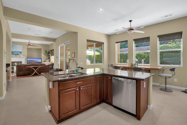 kitchen featuring stainless steel dishwasher, ceiling fan, dark stone countertops, and sink