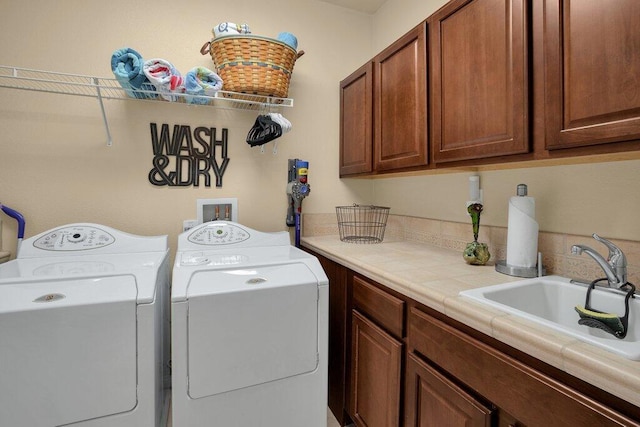 clothes washing area with washing machine and dryer, sink, and cabinets