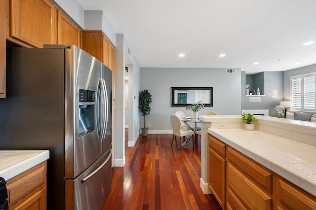 kitchen featuring stainless steel fridge with ice dispenser, dark hardwood / wood-style floors, and tile countertops