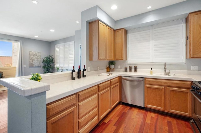 kitchen with black stove, sink, dark hardwood / wood-style floors, kitchen peninsula, and stainless steel dishwasher