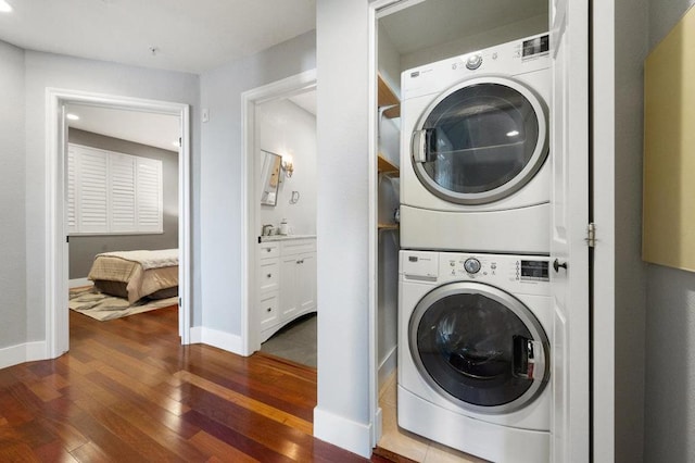 washroom with dark wood-type flooring and stacked washer and clothes dryer