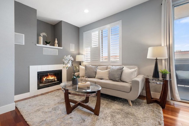 living room with hardwood / wood-style flooring, a healthy amount of sunlight, and a tile fireplace