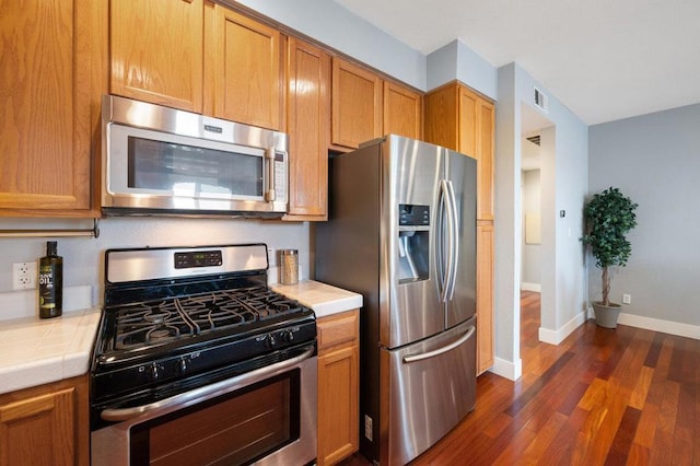 kitchen featuring dark hardwood / wood-style flooring, tile counters, and stainless steel appliances