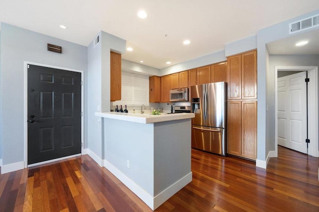 kitchen featuring kitchen peninsula, sink, dark hardwood / wood-style floors, and stainless steel appliances