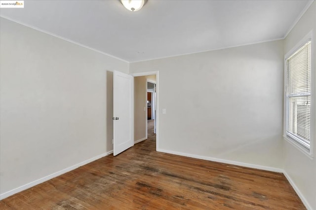 unfurnished room with crown molding and dark wood-type flooring