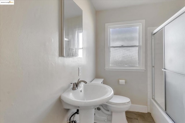 bathroom featuring tile patterned floors, bath / shower combo with glass door, and toilet