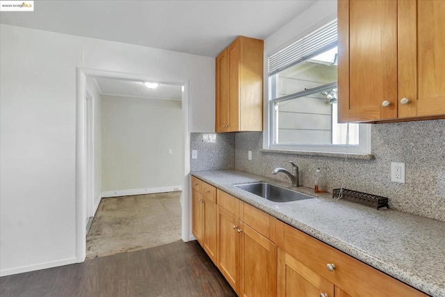 kitchen featuring light stone countertops, backsplash, dark wood-type flooring, and sink