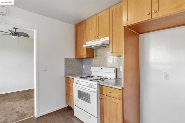 kitchen with ceiling fan, white gas stove, light brown cabinets, dark hardwood / wood-style floors, and backsplash