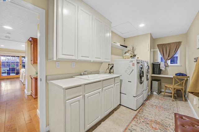 washroom with cabinets, washing machine and dryer, light hardwood / wood-style flooring, and sink