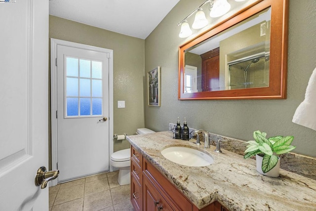 bathroom featuring tile patterned floors, vanity, toilet, and a shower with door