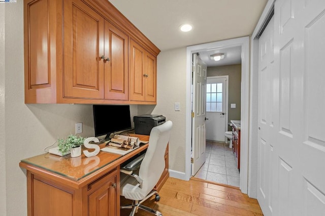 home office with built in desk and light hardwood / wood-style flooring