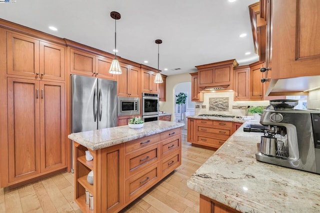 kitchen featuring light stone counters, a center island, pendant lighting, and appliances with stainless steel finishes