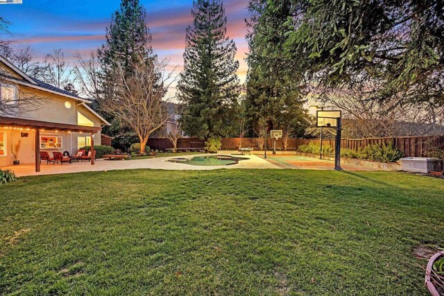 yard at dusk featuring a patio and a fenced in pool