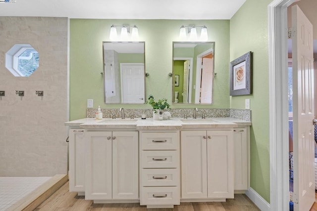 bathroom with hardwood / wood-style floors, vanity, and a tile shower