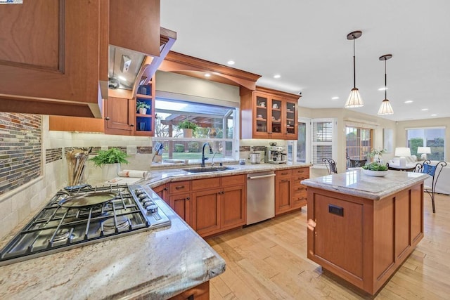 kitchen with light stone countertops, tasteful backsplash, stainless steel appliances, pendant lighting, and a center island