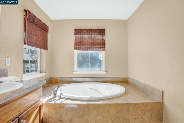 bathroom with tiled tub and vanity