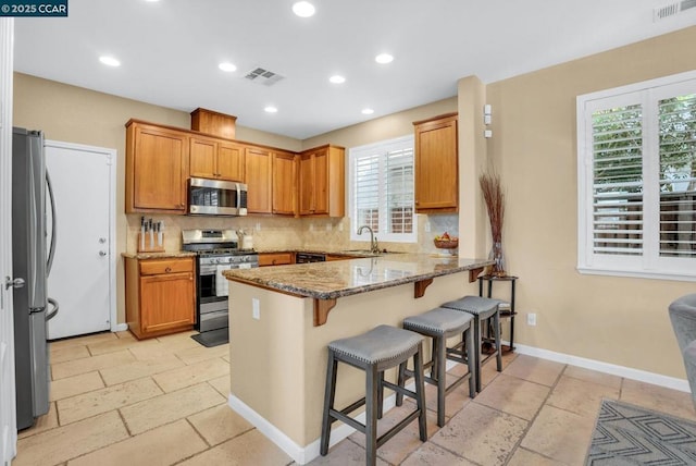 kitchen with a kitchen bar, stainless steel appliances, plenty of natural light, and stone countertops