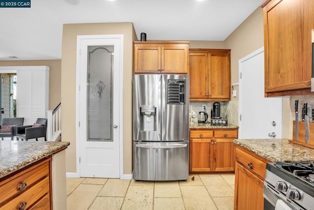 kitchen featuring stainless steel appliances, light stone counters, and tasteful backsplash