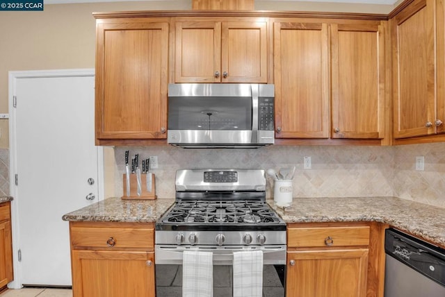 kitchen with tasteful backsplash, light stone countertops, and appliances with stainless steel finishes