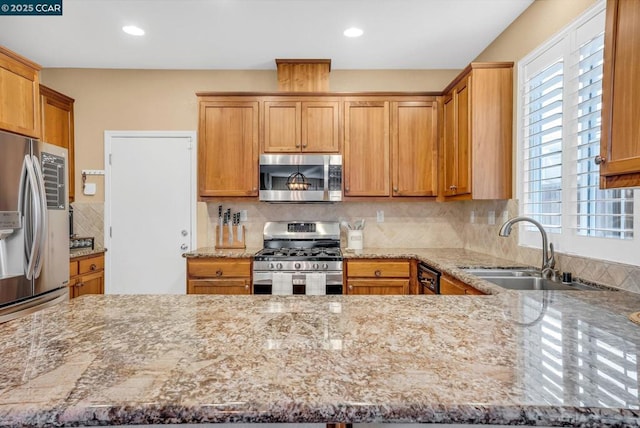 kitchen with light stone countertops, appliances with stainless steel finishes, kitchen peninsula, tasteful backsplash, and sink