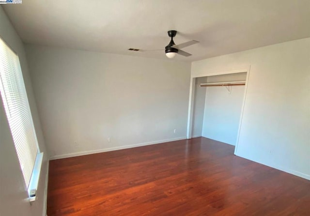 unfurnished bedroom featuring ceiling fan, a closet, and dark wood-type flooring