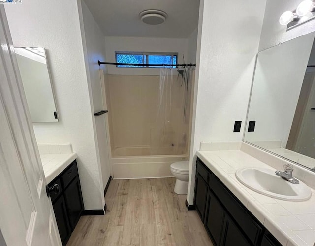 full bathroom with hardwood / wood-style flooring, vanity, toilet, and washtub / shower combination